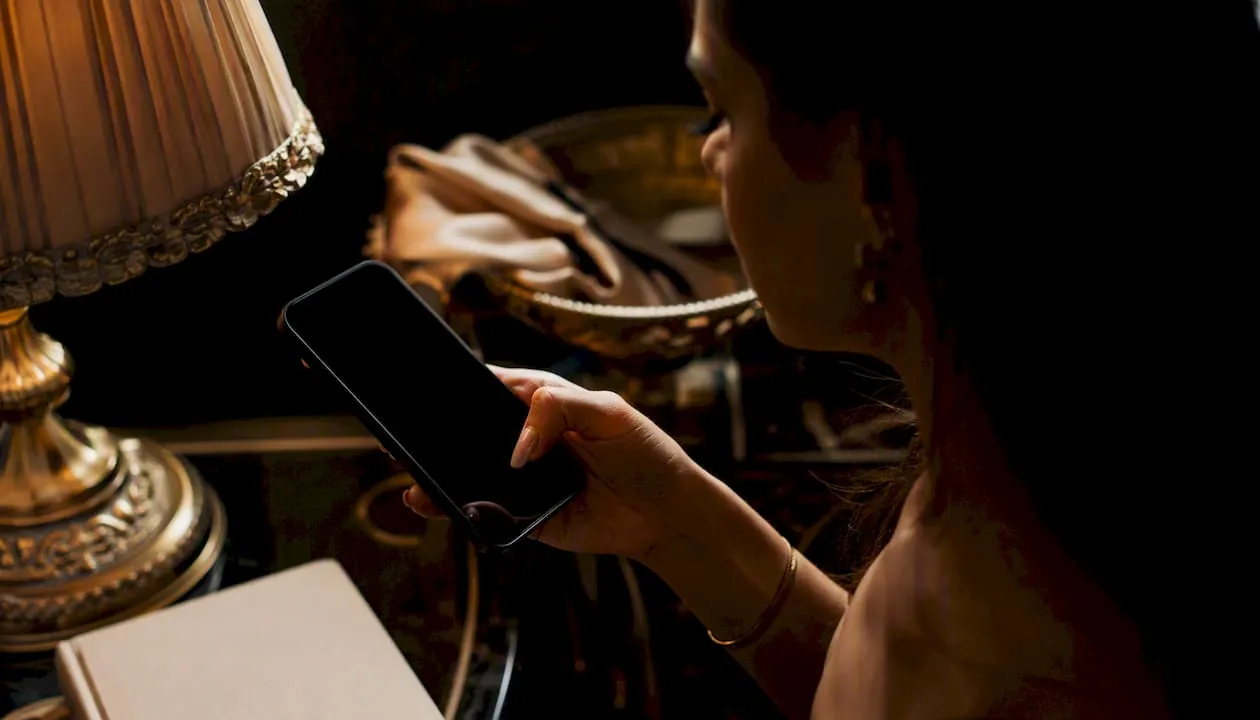 Hand unlocking iPhone with Face ID in warm dark room